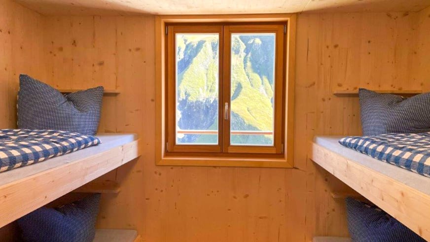Innenraum eines Mehrbettzimmers in der Kemptner Hütte mit Etagenbetten aus hellem Holz.