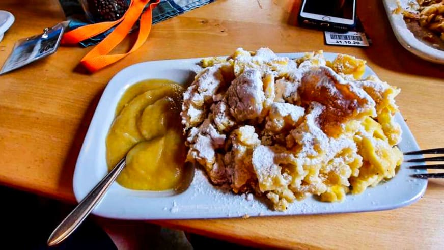Kaiserschmarrn mit Puderzucker und Pflaumenkompott auf Holztisch im Gastraum der Braunschweiger Hütte.