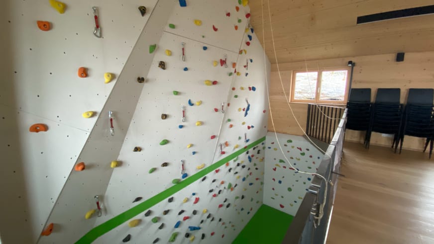 Kletterhalle in der Warnsdorfer Hütte mit überhängender Wand und bunten Griffen für das Training.