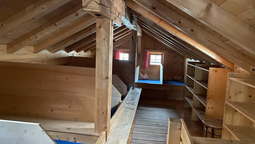 Matratzenlager der Warnsdorfer Hütte im Dachgeschoss mit mehrstöckigen Holzbetten und blauen Matratzen.
