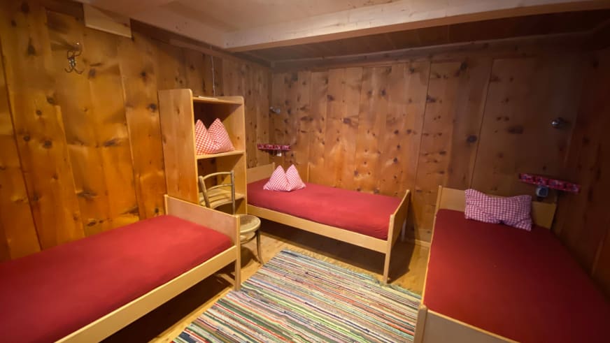 Mehrbettzimmer der Warnsdorfer Hütte mit vier Einzelbetten in Etagenbetten aus naturbelassenem Holz.