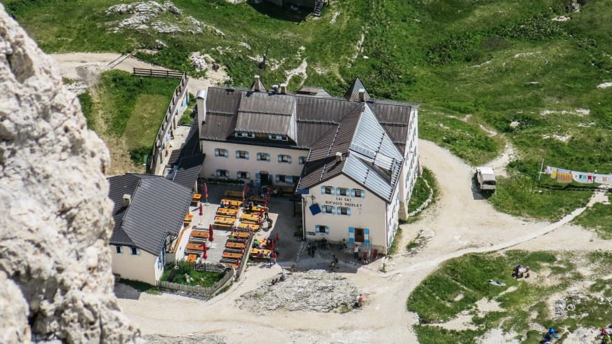 Luftbild des Rifugio Vajolet zeigt die Sonnenterrasse mit orangen Holztischen von oben.