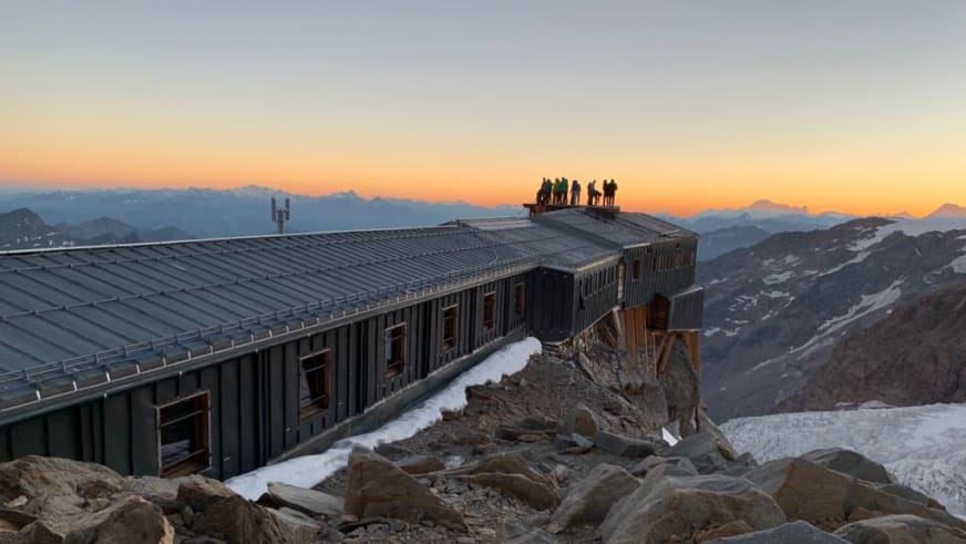 Bergsteiger auf dem Dach der Capanna Gnifetti bei Sonnenaufgang in den Walliser Alpen.