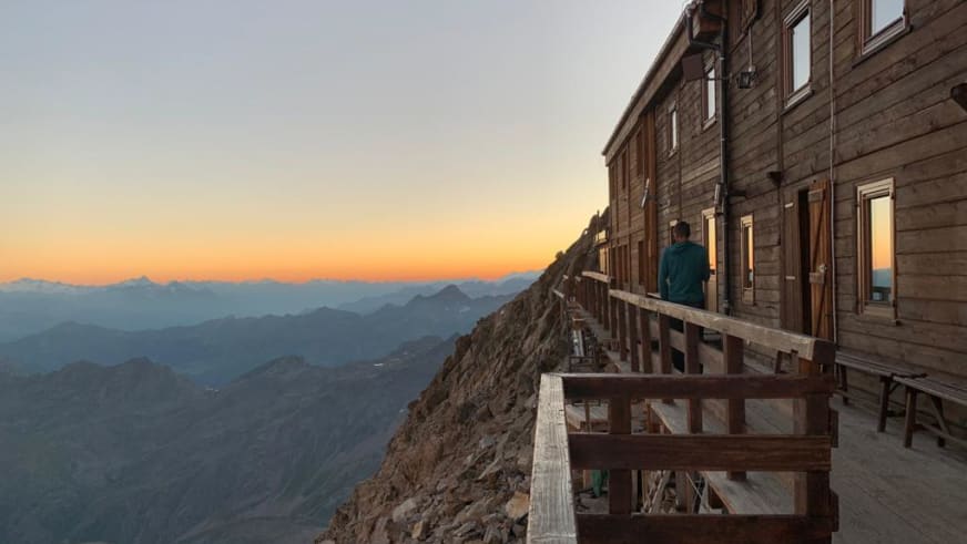 Wanderer auf der Terrasse der Capanna Gnifetti mit Bergpanorama bei Sonnenuntergang.