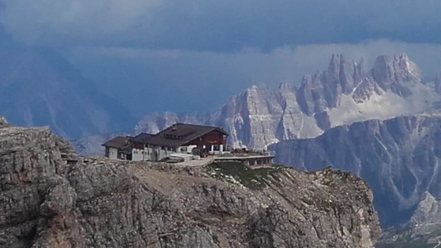Das Rifugio Lagazuoi steht auf einem schmalen Dolomitfelsgrat mit steilen Gipfeln im Hintergrund.