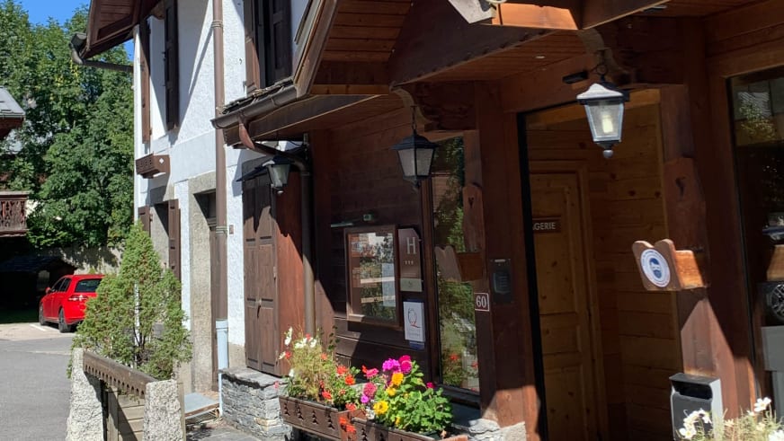 Eingangsbereich des Hotel de L'Arve Chamonix mit traditioneller Chalet-Architektur und bunten Blumenkästen.