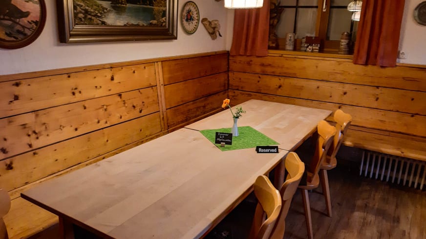 Gemütlicher Gastraum der Albert-Link-Hütte mit Eckbank, Holztisch und alpiner Wandverkleidung.