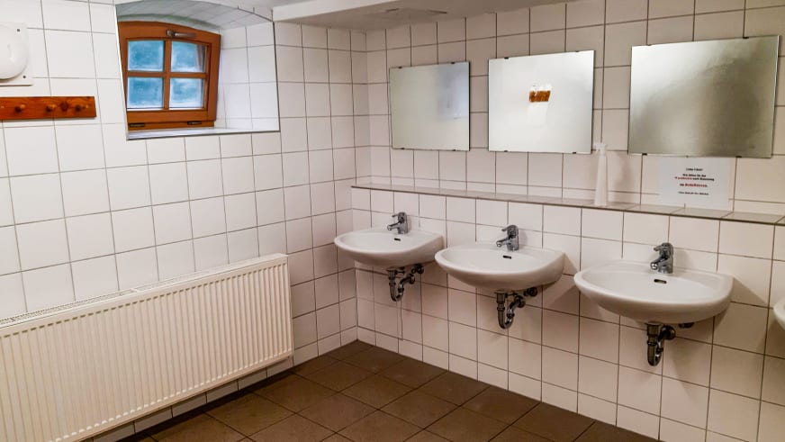 Sauberer Gemeinschaftswaschraum in der Albert-Link-Hütte mit drei Waschbecken und gefliesten Wänden.