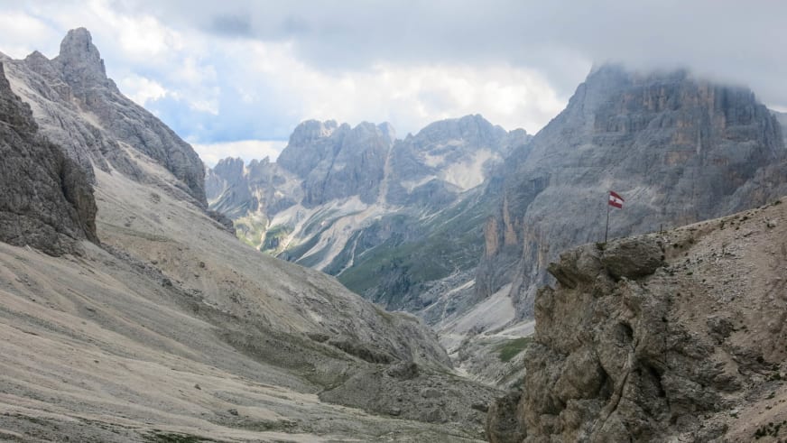 Blick von der Grasleitenpasshütte ins Vajolet-Tal mit steilen Dolomitfelswänden und schuttbedecktem Hang im Vordergrund.