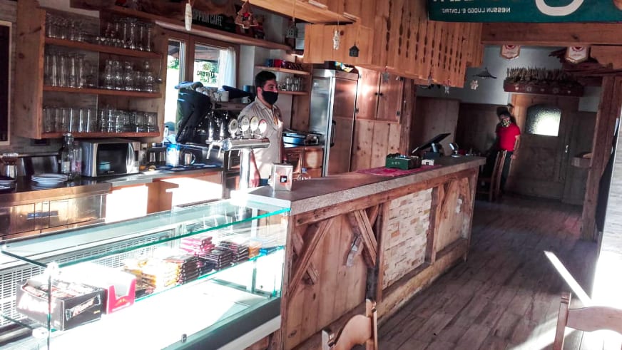 Holztresen mit Espressomaschine und Vitrine im Rifugio Col Gallina zeigt traditionelle Hüttenausstattung.