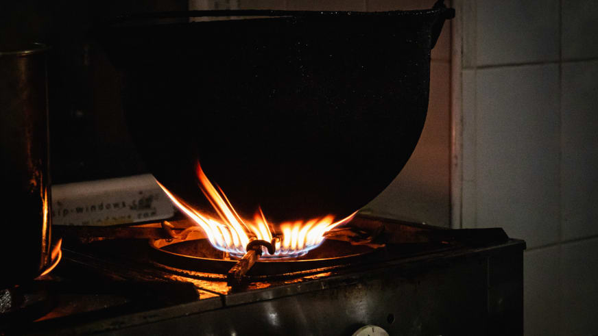 Gasflamme brennt unter schwarzem Topf auf dem Herd in der funktionalen Küche der Cabana Negoiu.