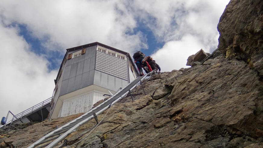Bergsteiger klettern über steile Felsen mit Drahtseil zur Cabane de Bertol hinauf.