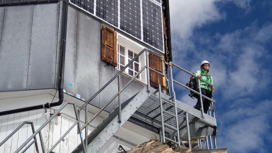 Bergsteiger auf der Außentreppe der Cabane de Bertol mit moderner Metallverkleidung.