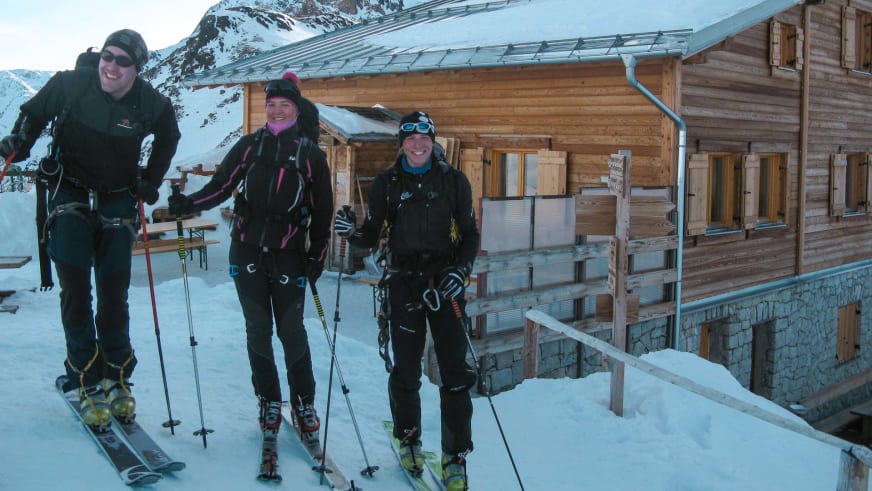 Drei Skitourengeher stehen vor der Martellerhütte auf 2.585 m im verschneiten Ortlergebiet bei klarem Winterwetter.