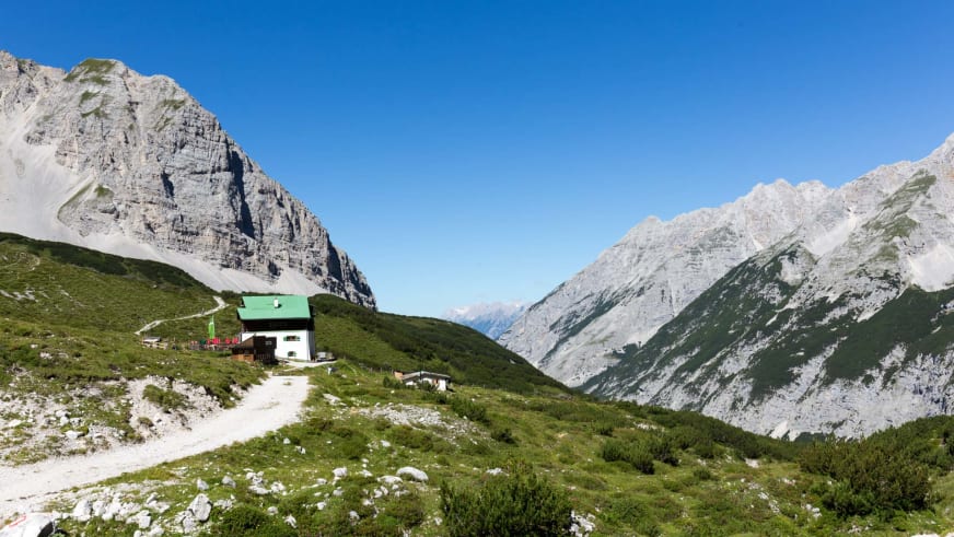 Panoramablick auf die Pfeishütte mit grünem Dach inmitten der Karwendel Kalksteinwände.