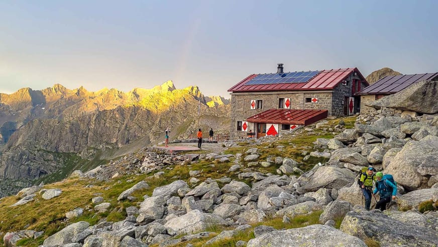 Bergwanderer mit Rucksäcken durchqueren ein Blockfeld vor dem Rifugio Gianetti auf 2.534 m in den Bernina-Alpen.