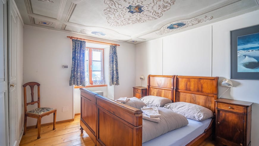 Elegantes Doppelzimmer im Albergo San Gottardo mit verzierter Kassettendecke und traditioneller Holzausstattung.