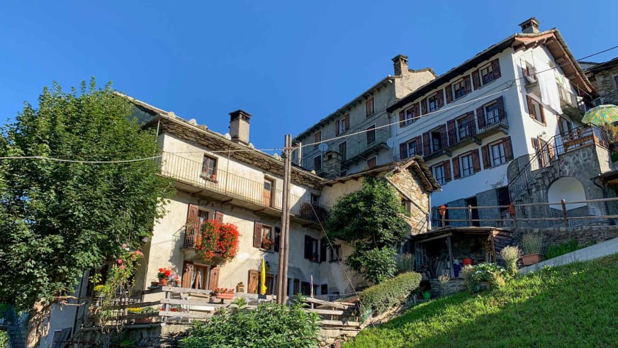 Außenansicht des Albergo Fontana mit traditioneller Walser Architektur und sonniger Terrasse in Rimella.