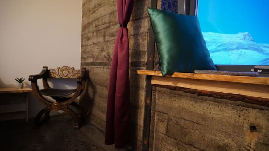Gemütlicher Aufenthaltsbereich in der Holy Ram Lodge mit Steinbank, Holzmöbeln und traditioneller isländischer Einrichtu