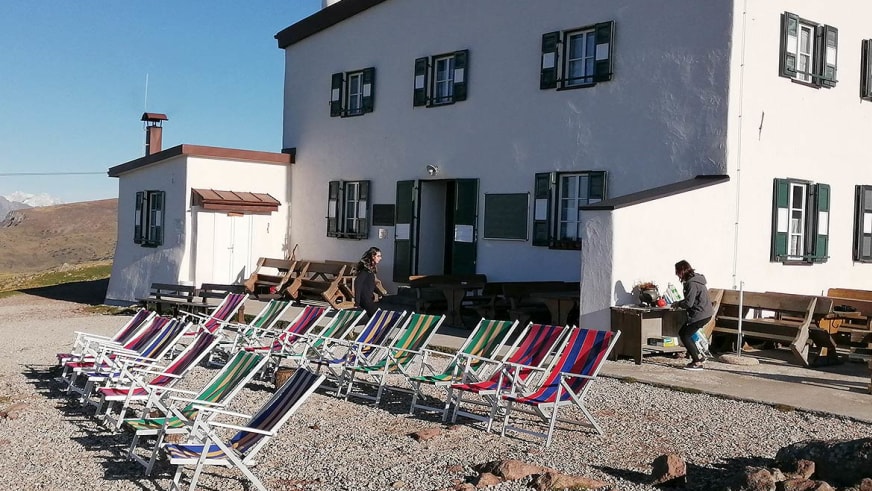 Bunte Liegestühle stehen vor dem Schutzhaus Rittner Horn auf der Sonnenterrasse.