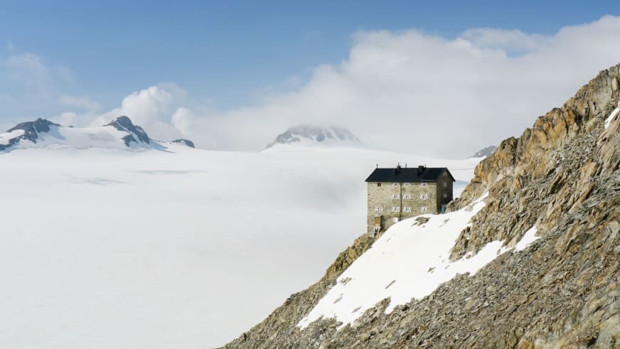 Blick auf das Brandenburger Haus zwischen steiler Felswand und weiter Gletscherlandschaft der Ötztaler Alpen.