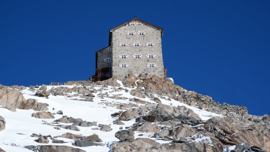 Ansicht des Brandenburger Haus von unten zeigt die mehrstöckige Natursteinfassade mit roten Fensterläden.