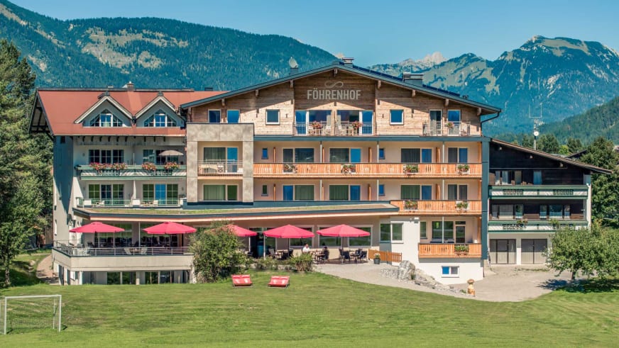 Außenansicht des Hotel Föhrenhof mit roter Sonnenterrasse und Blick auf die Lechtaler Alpen.