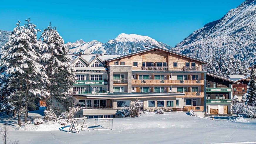 Das Hotel Föhrenhof im Winterkleid mit verschneiter Landschaft und Bergpanorama der Lechtaler Alpen.