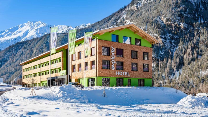 Winteraufnahme vom Explorer Hotel Stubaital mit verschneiter Bergkulisse der Stubaier Alpen.