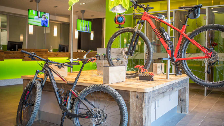 Hotellobby im Explorer Hotel Stubaital mit ausgestellten Mountainbikes und Holzmöbeln.