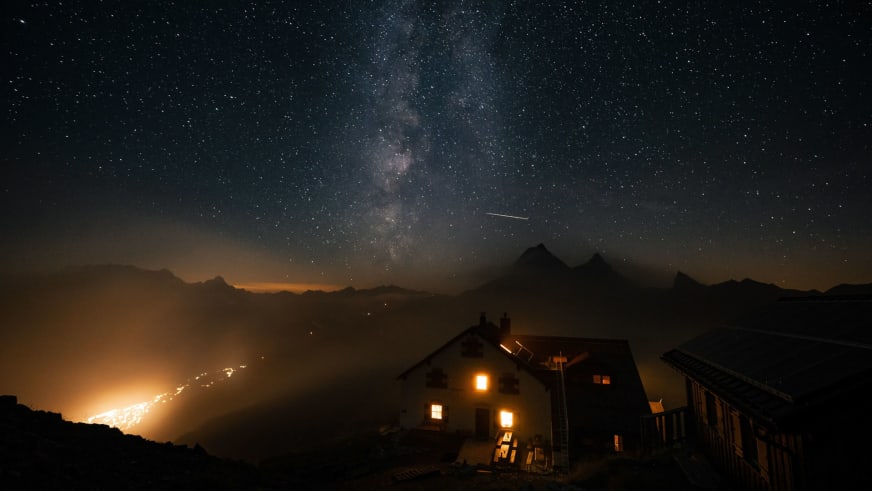 Nachtaufnahme der beleuchteten Leutkircher Hütte unter sternenklarem Himmel mit sichtbarer Milchstraße über den Lechtale