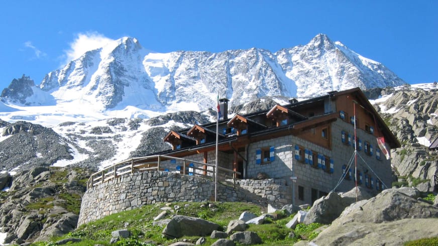 Das Rifugio Stavèl Denza auf 2.298 m mit schneebedeckter Presanella und Gletschern im Hintergrund der Adamello-Presanell
