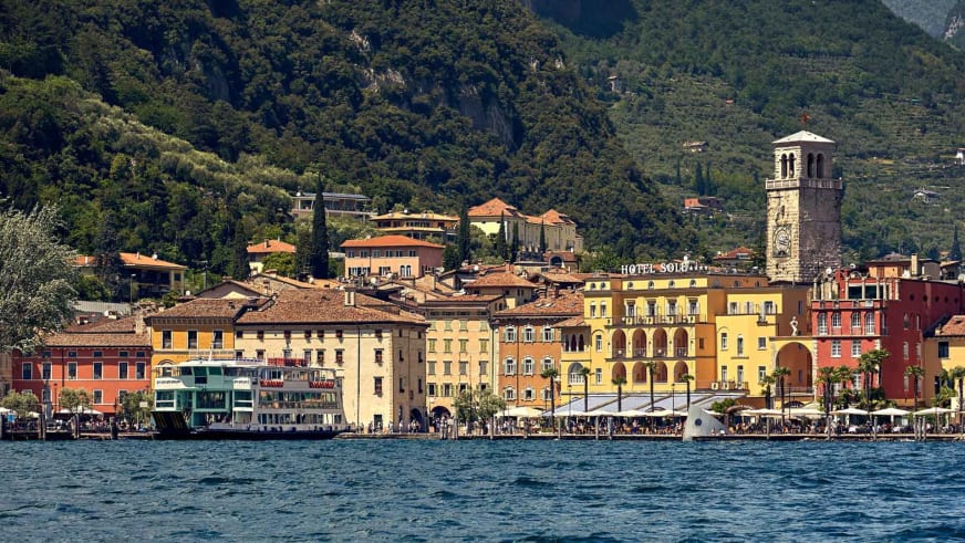 Bunte Hotelfront der Garda Hotels Riva **** direkt am türkisblauen Gardasee mit mediterraner Architektur.
