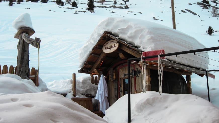 Außenansicht der finnischen Sauna am Rifugio Lavarella umgeben von meterhohen Schneemassen im Winter.