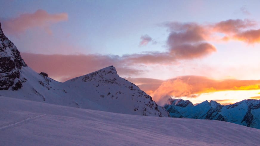 Verschneite Hochgebirgslandschaft bei der Skitour zum Strahlhorn mit Blick zurück zur Britannia-Hütte in der Dämmerung.