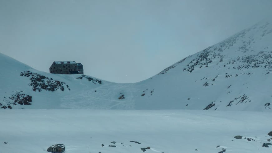 Winteransicht der Britannia-Hütte auf einem Felsvorsprung unterhalb des Allalinhorn mit schneebedeckter Umgebung.