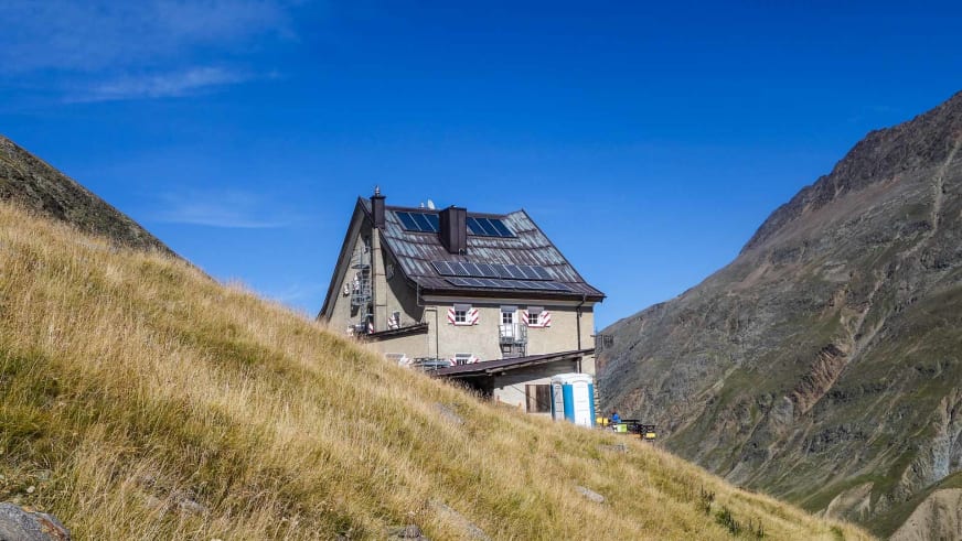 Das Hochjoch Hospiz liegt in steiler Hanglage zwischen hohen Bergen mit Solarpaneelen auf dem Dach.