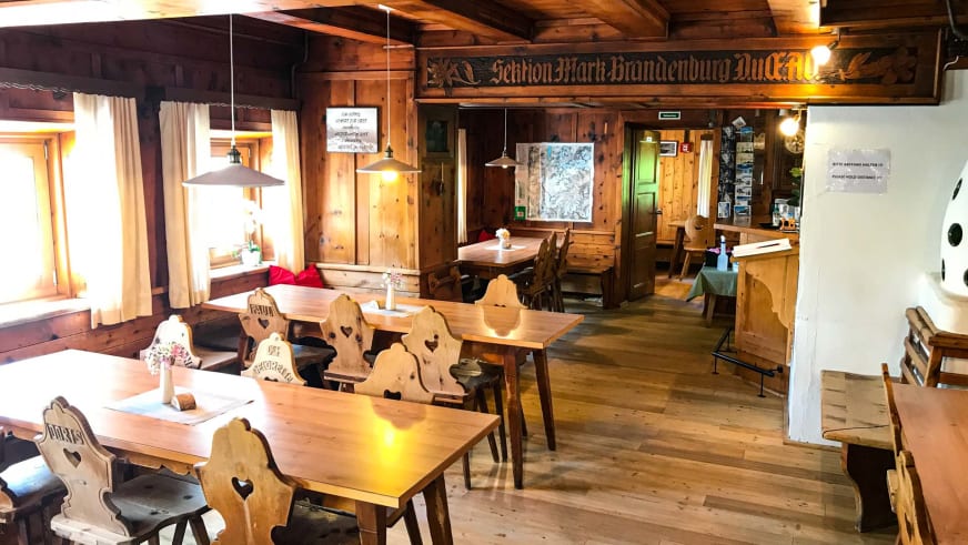 Traditioneller Gastraum im Hochjoch Hospiz mit geschnitzten Holzstühlen und alpiner Einrichtung in warmer Atmosphäre.