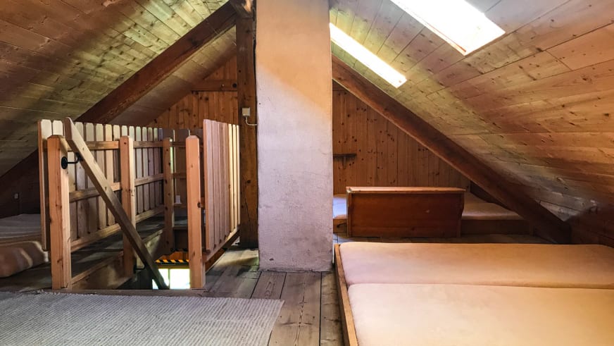Einfaches Matratzenlager im Hochjoch Hospiz unter dem Dach mit Holzbetten und Dachsparren.