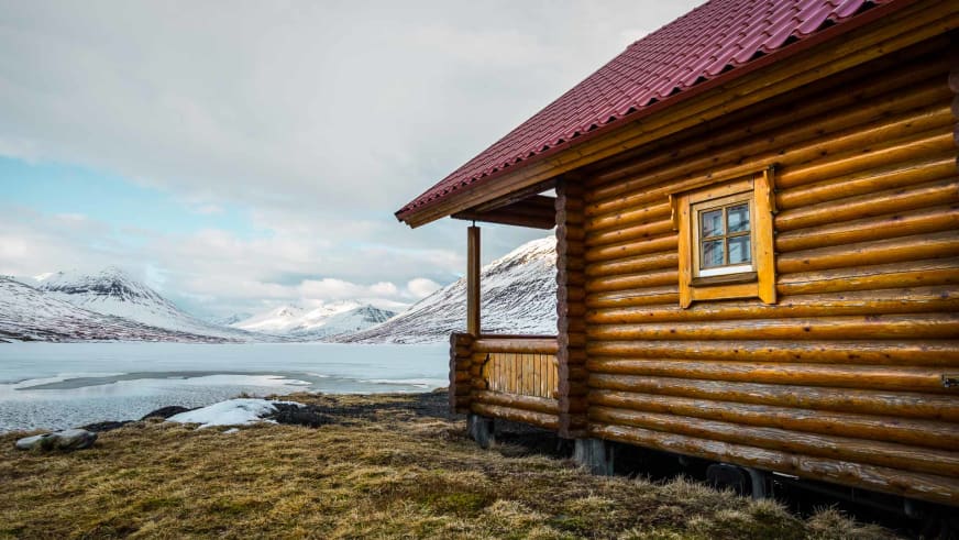 Das Rundholz-Blockhaus des Brimnes Hotel and Cabins steht am zugefrorenen See in Island.