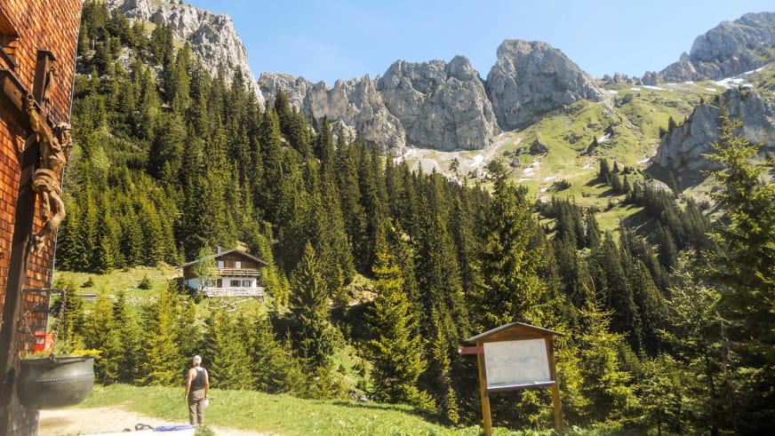 Bergwanderer auf der Terrasse vom Gimpelhaus mit Blick auf bewaldete Hänge und Kalksteinwände im Tannheimer Tal.