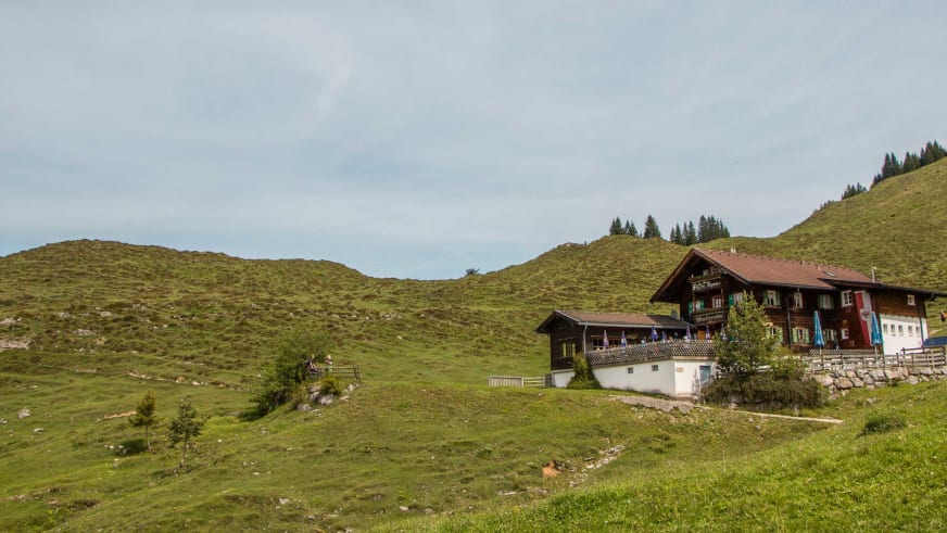 Panoramablick über die Walleralm mit Berghütten auf grünen Almwiesen im Kaisergebirge.