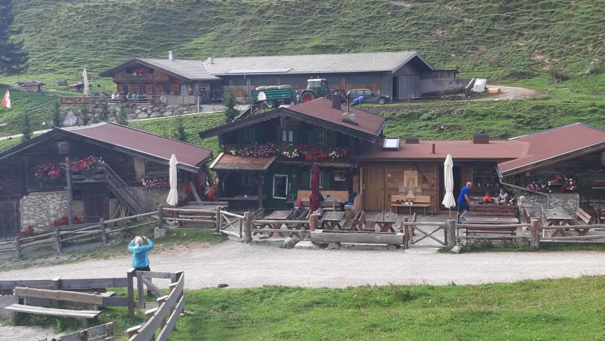 Weitläufige Holzterrasse der Walleralm mit Tischen, Bänken und weißen Sonnenschirmen.
