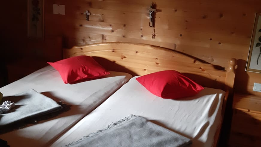 Doppelzimmer der Walleralm mit zwei Einzelbetten aus Zirbenholz und weißer Bettwäsche.