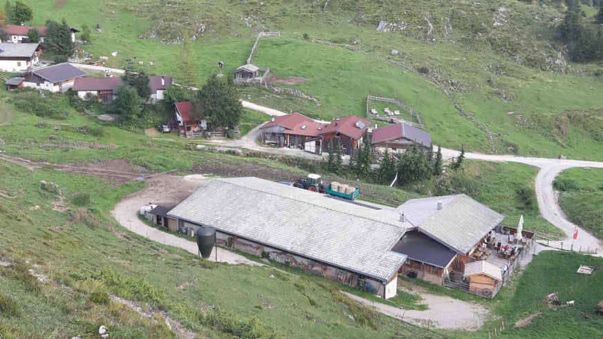 Luftaufnahme der Walleralm mit großem Satteldach inmitten grüner Almwiesen und sanften Hügeln.