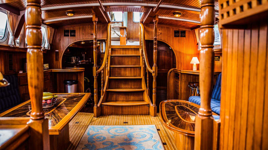 Der Salon der Ylva zeigt eine breite Holztreppe mit gedrechselten Geländern und einen Navigationsbereich mit nautischen Instrumenten.