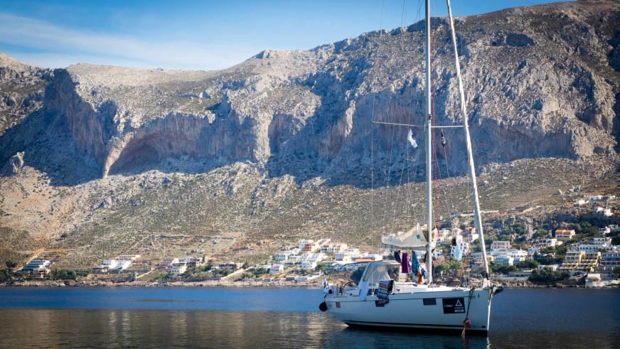 Weißer Segelkatamaran der griechischen Yacht ankert vor der Küstensiedlung von Kalymnos in ruhigem Wasser.