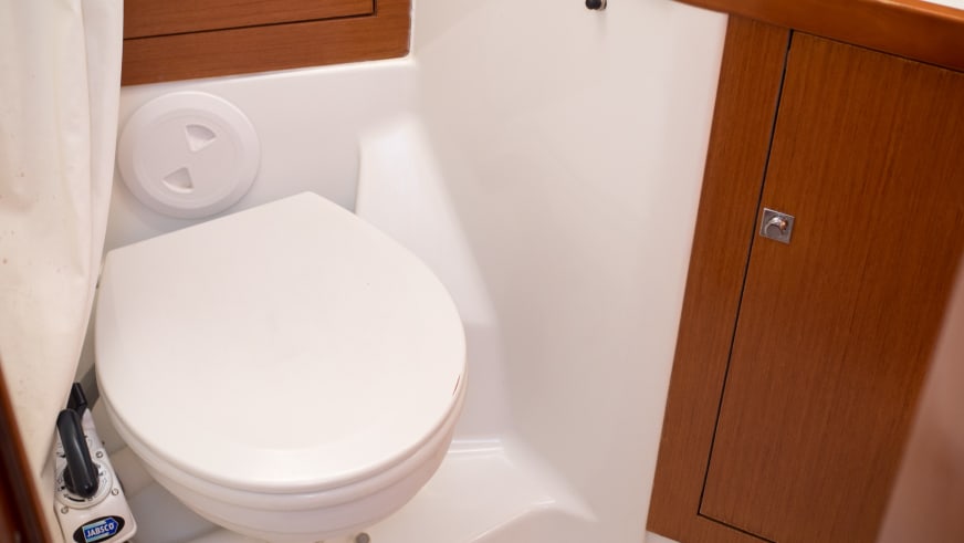 Kompakte Toilette mit weißer Keramik und Holzschrank an Bord der griechischen Yacht auf Kalymnos.