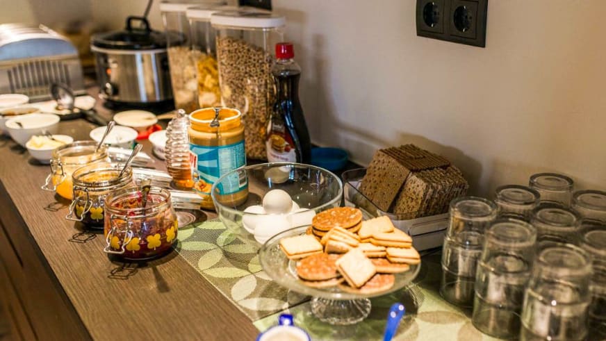 Frühstücksbuffet mit Käse, Marmelade, Eiern und Müsli im Hotel Duus by Keflavik Airport auf einem Holztisch arrangiert.