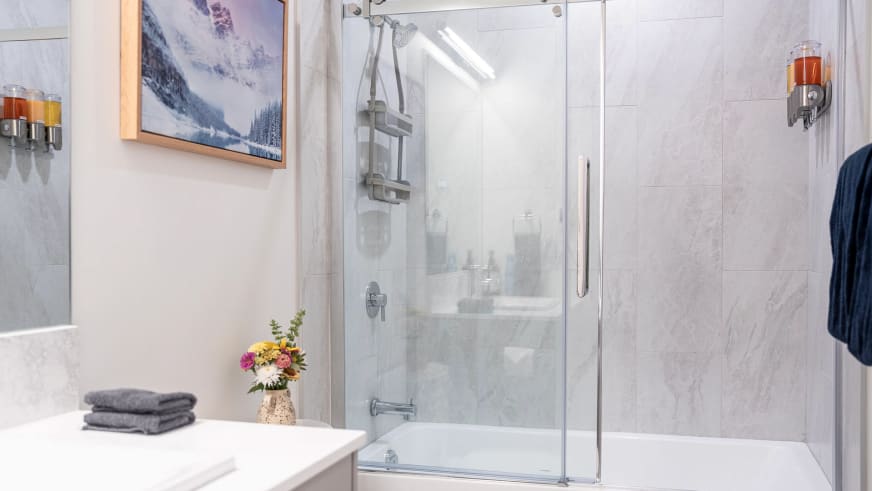 Badezimmer im Stoked Penthouse Revelstoke mit Badewanne-Dusch-Kombination und Marmoroptik-Fliesen.